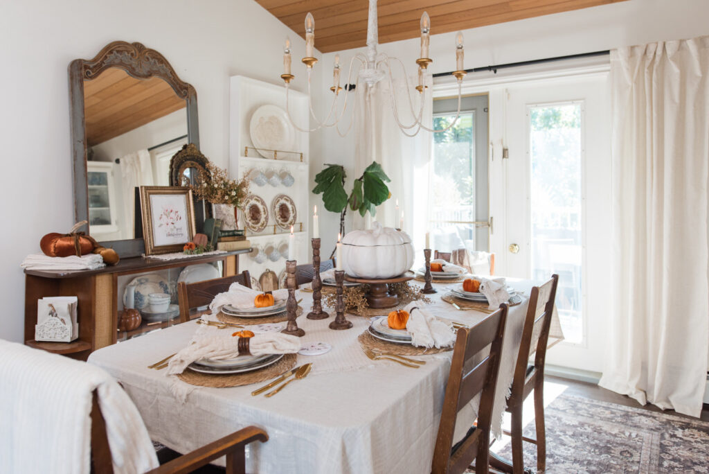 Autumn dining room decor with a set table, a china cabinet with a white plate rack, and a large mirror