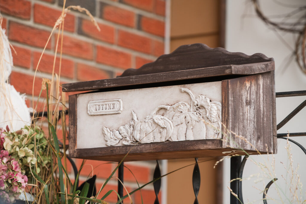 Close-up of a handmade autumn mailbox insert with sculpted pumpkins and the word Autumn