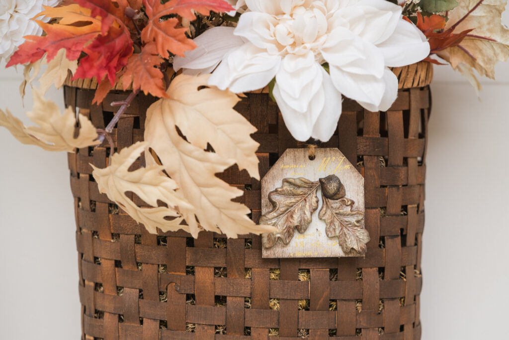 Basket of fall florals with a handmade tag hanging on a white front door
