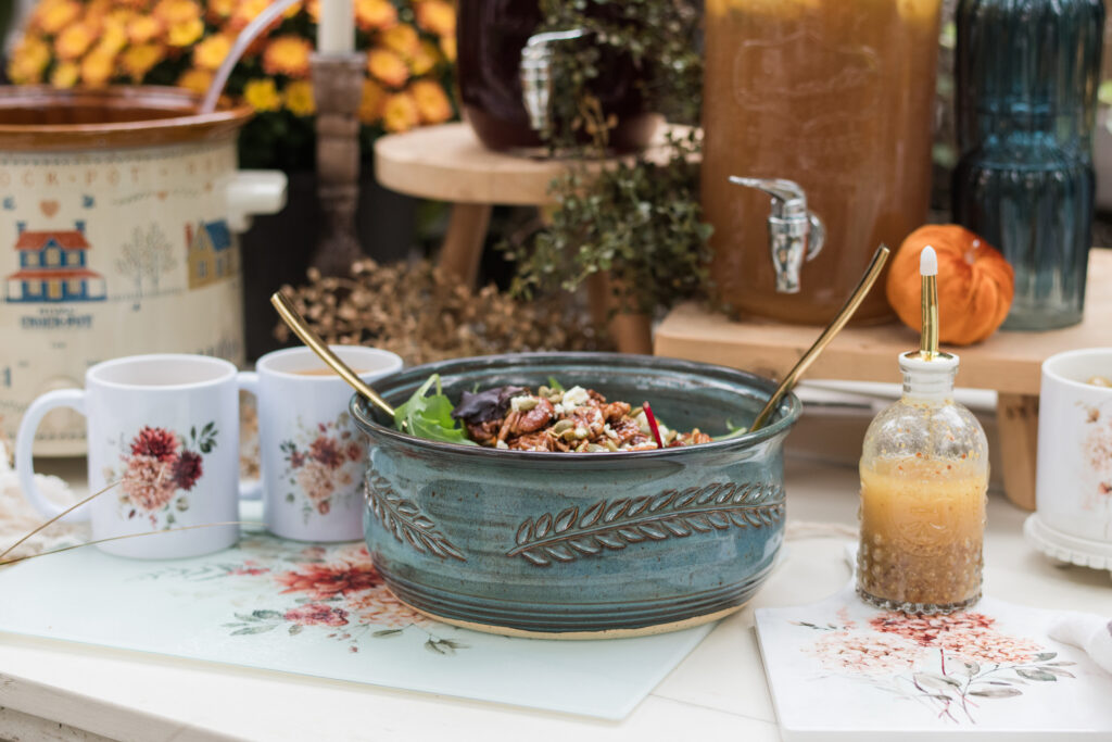 Close-up of a Spicy Floral glass cutting board used as a trivet under a salad bowl and a Spicy Floral mug on an autumn buffet