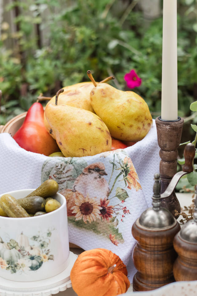 Close-up of a Pumpkin Patch bird tea towel on an autumn buffet beside pumpkins and florals