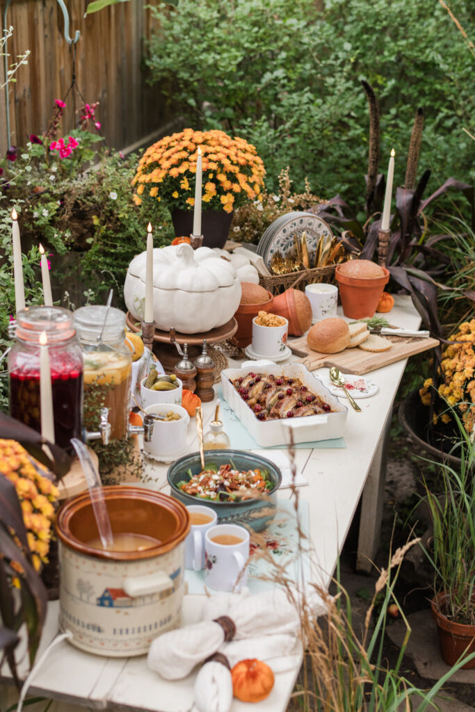Autumn buffet mixing Vintage Autumn, Spicy Floral, and Magnolia pieces, with glass cutting boards used as trivets under the pork tenderloin and the salad, a canister of serving spoons, and a forest wood engraved cutting board holding sage bread