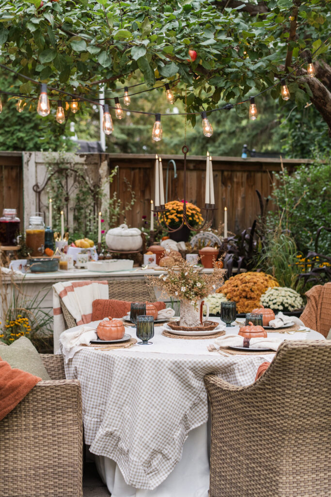 Chandelier with battery-operated tapers hanging above an outdoor table in the evening