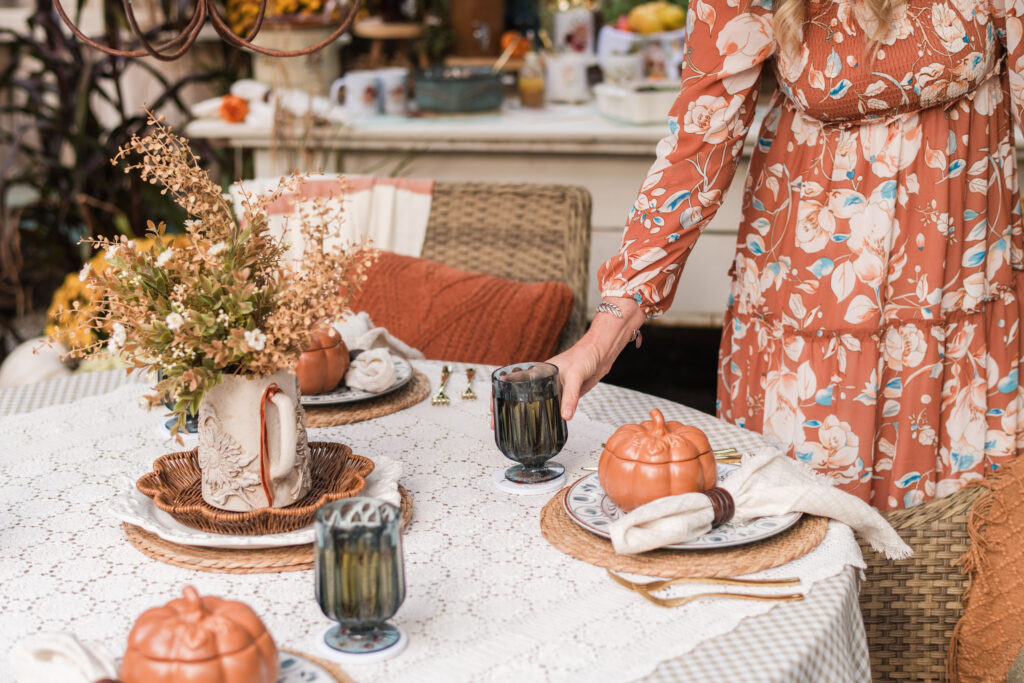 Kimberly setting a glass of a fall drink on an outdoor dinner table