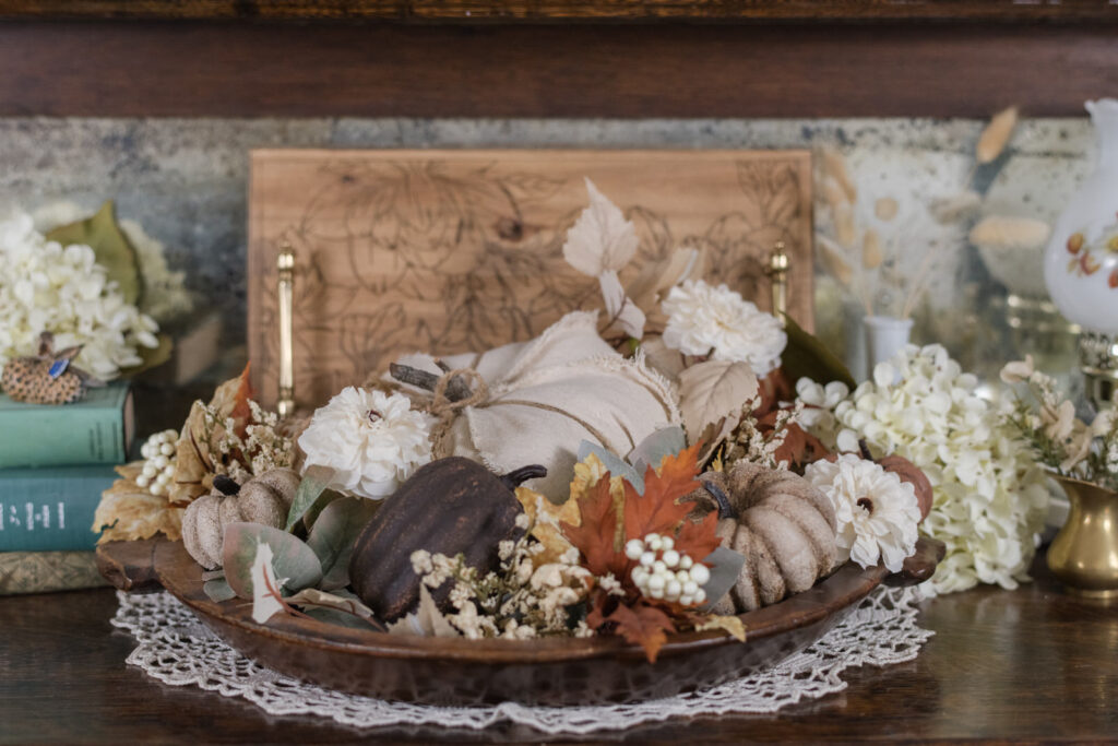Pumpkin and autumn greenery styled in a wood tray on top of a vintage hutch