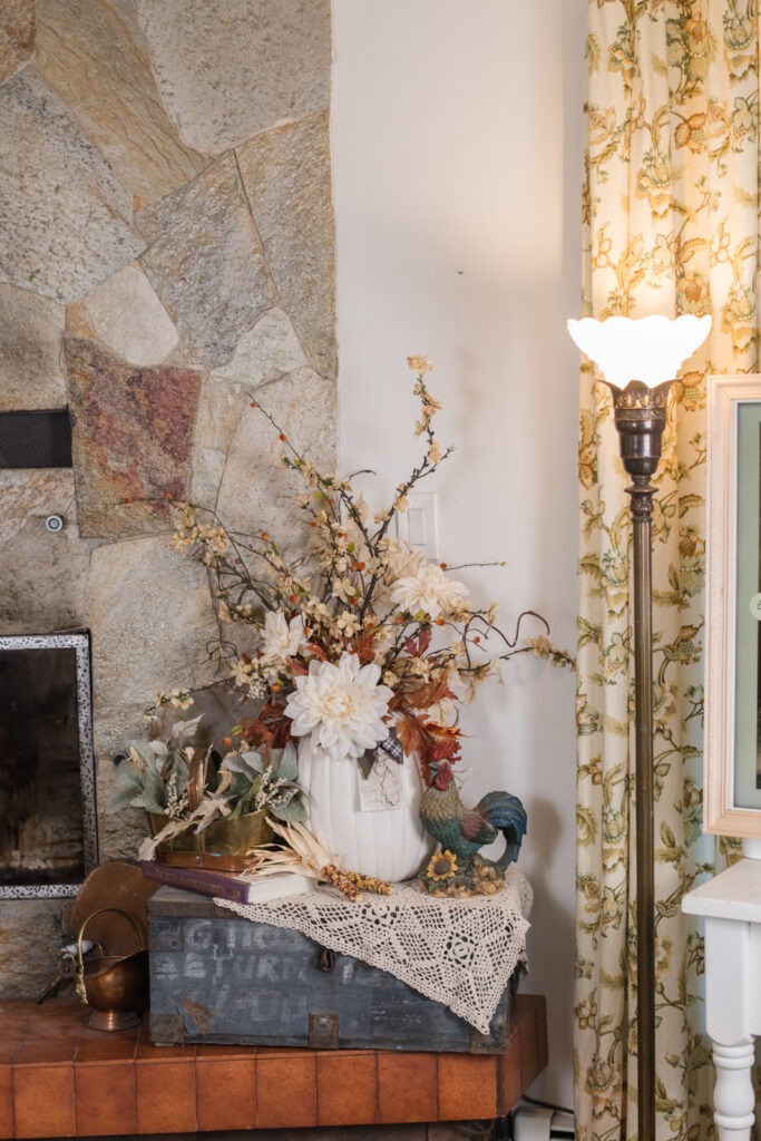 Vintage lamp and a large autumn arrangement beside a stone fireplace in a family room decorated for autumn