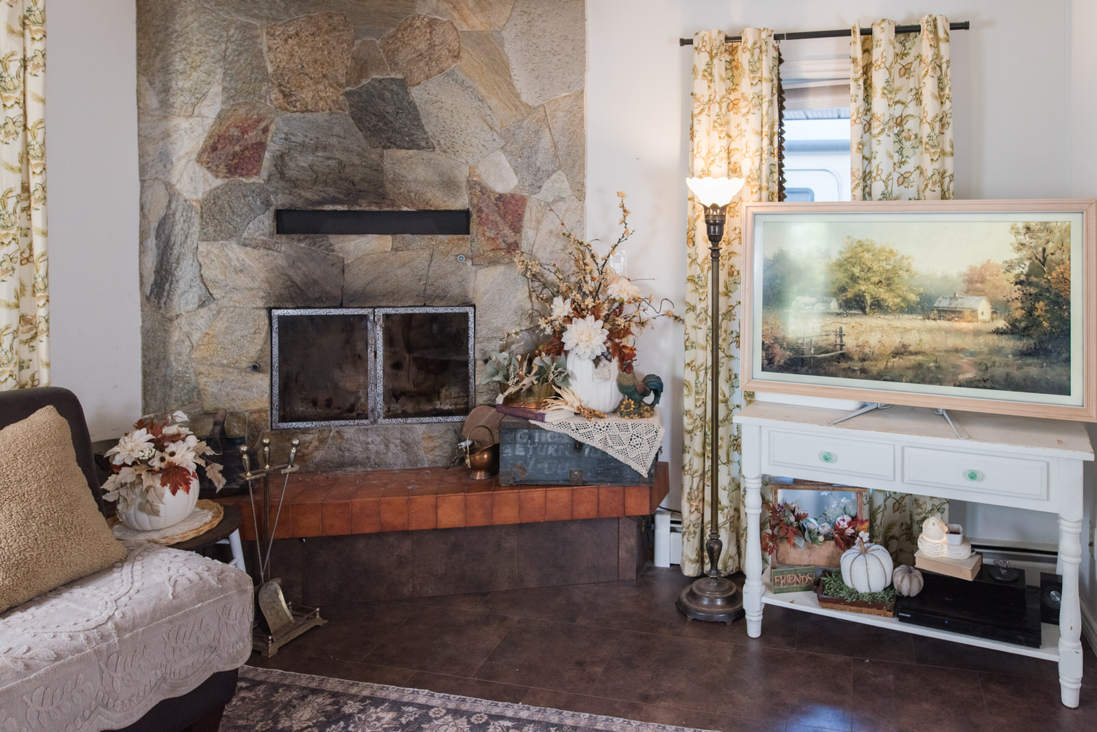 Family room decorated for fall with a stone fireplace art on the frame TV for autumn