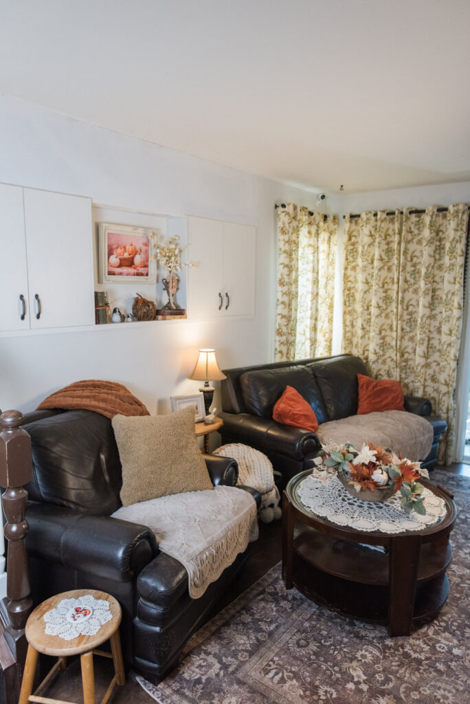 Cozy family room with a love seat, a chair, and a coffee table in front of a built-in cabinet, styled for autumn