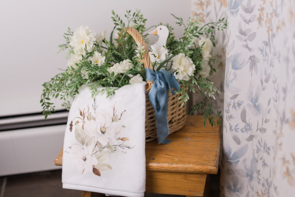 Magnolia hand towel tucked into a basket with florals in a guest bathroom