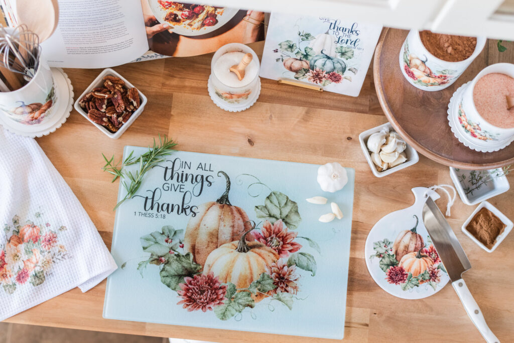 Warm Vintage Autumn pieces with orange pumpkins, including an In All Things Give Thanks glass cutting board and a Give Thanks to the Lord trivet